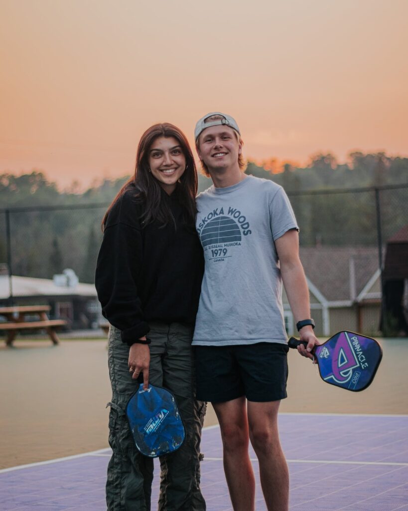 Young couple posing for a photo on a pickleball court.
